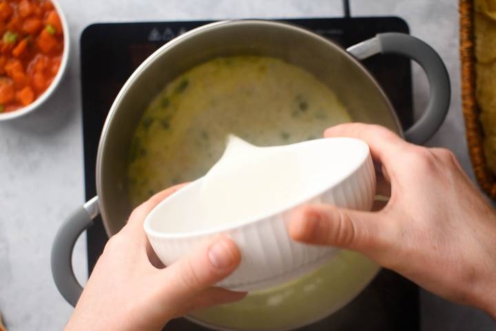 Chicken broth and milk being added to a pot.