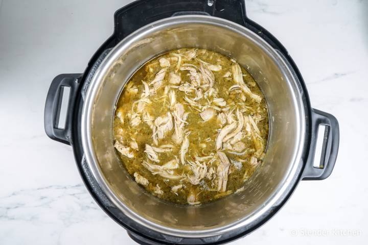 Shredded chicken in green salsa in a pressure cooker.