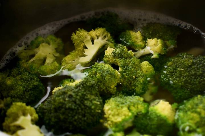 Broccoli cooking in a large pot with pasta.