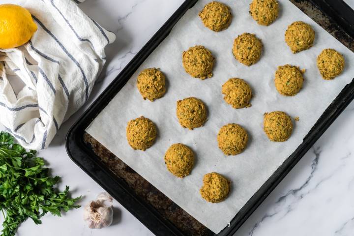 Crispy lentil falafel on a baking sheet with parchment paper.