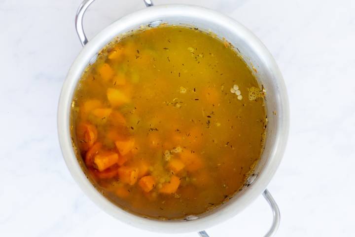 Lentil soup simmering in a soup pot.