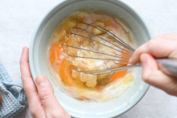 Wet ingredients for coconut muffins being whisked in a bowl.