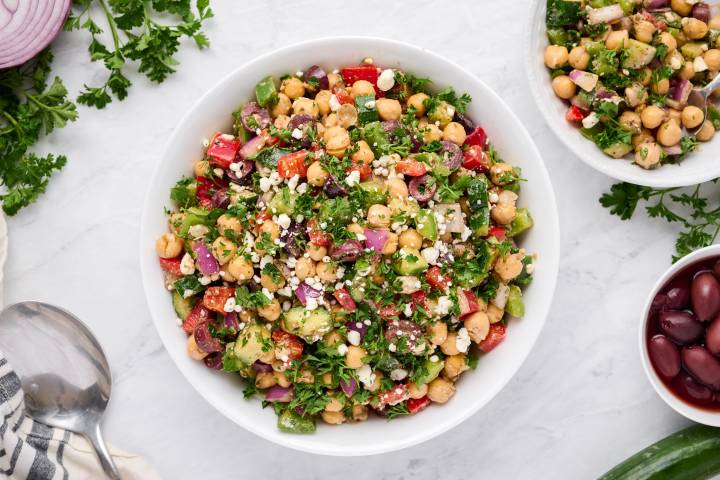 Mediterranean chickpea salad in a bowl with vegetables, feta cheese, and dressing.
