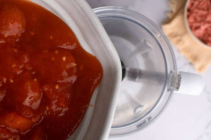 Chipotle tomato sauce being made in a blender with roasted tomatoes and chipotle peppers in adobo.
