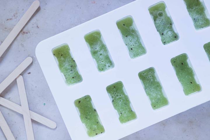 Cucumber and kiwi popsicles being made in a mold.