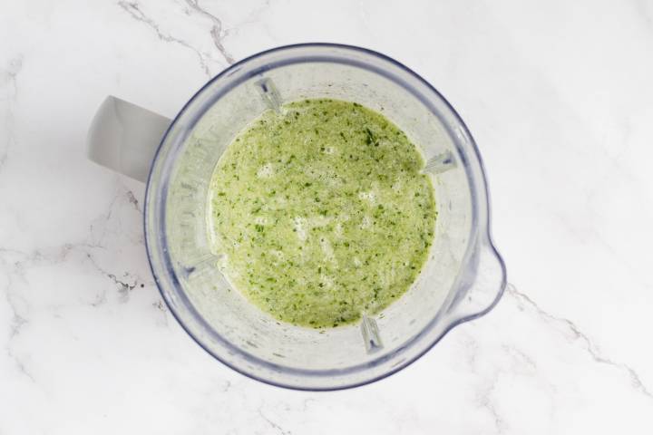 Spinach and coconut water blended together in a blender.