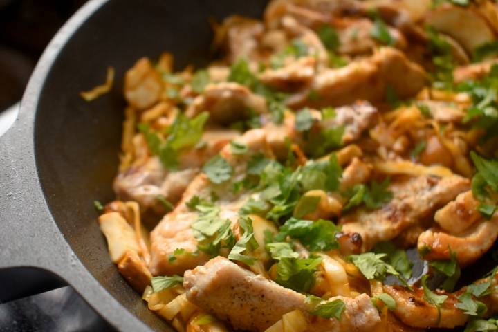 Moo shu pork in a skillet topped with fresh cilantro.