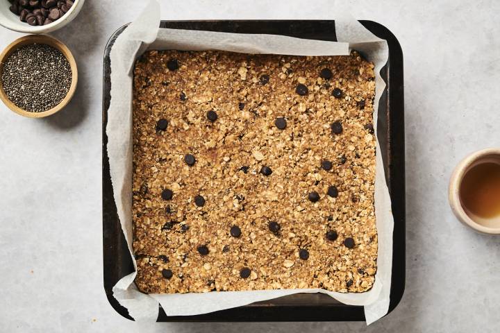 No bake oatmeal bars pressed into a baking dish with parchment paper.