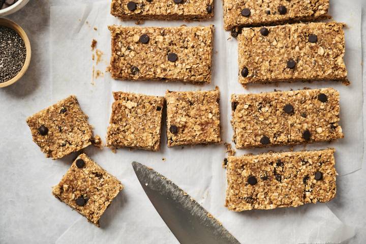 o bake chocolate chip oatmeal bars being cut into squares on a cutting board.