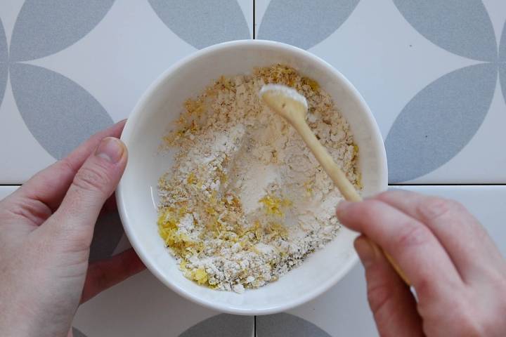 Flour, lemon zest, garlic powder, salt, and pepper being mixed in a bowl.