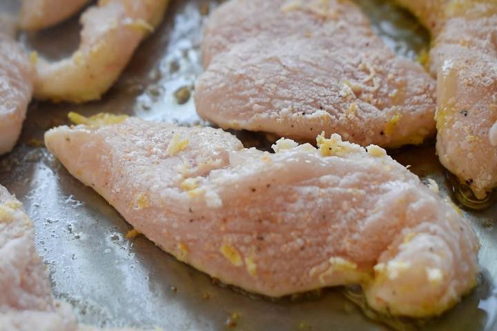 Chicken breast tenderloins cooking in a skillet.