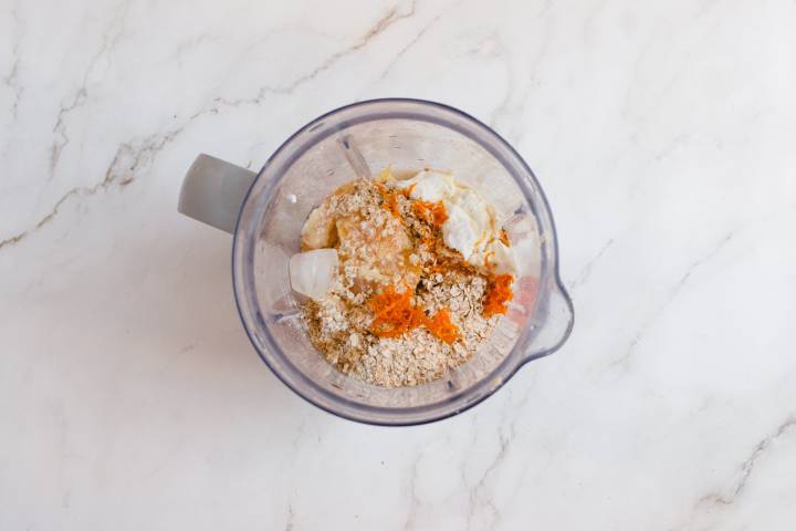 Oranges, bananas, oats, orange zest, yogurt, and almond milk in a blender.