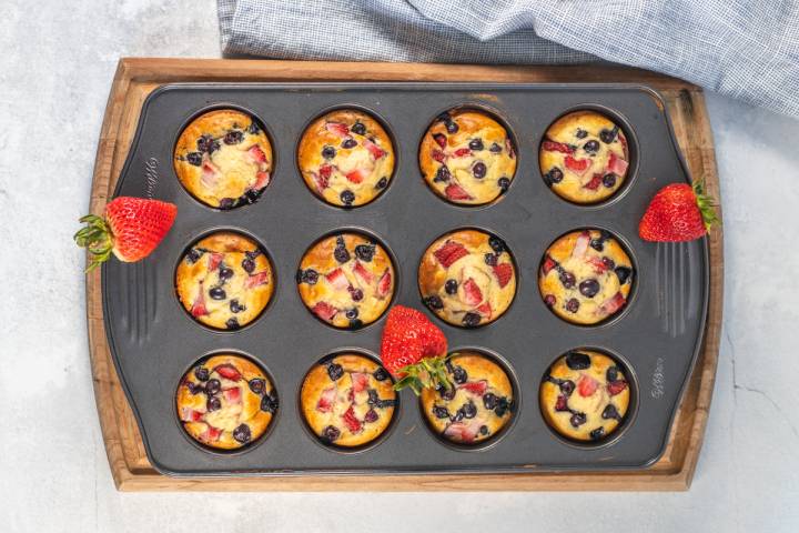 Pancake muffins with strawberries and blueberries cooked until golden brown in a muffin tin.