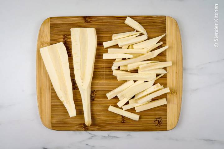 Parsnips on a cutting board that are peeled and cut into match sticks.