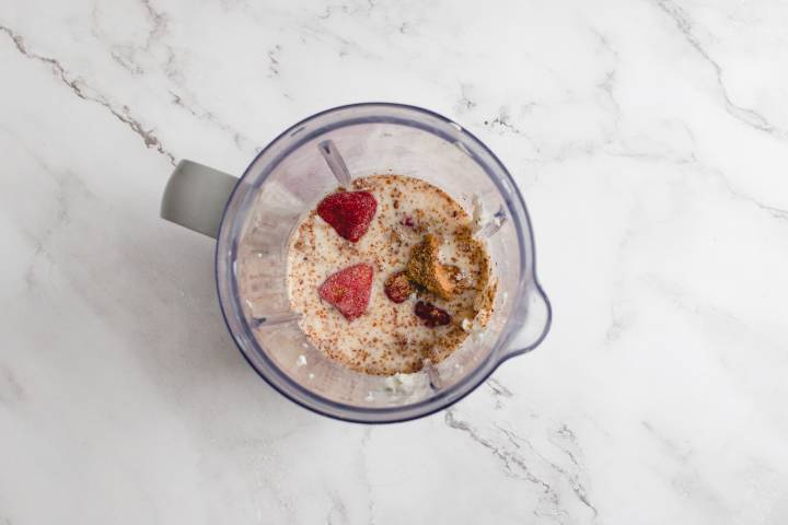 Strawberries, Greek yogurt, peanut butter, flaxseed meal, and almond milk in a blender.