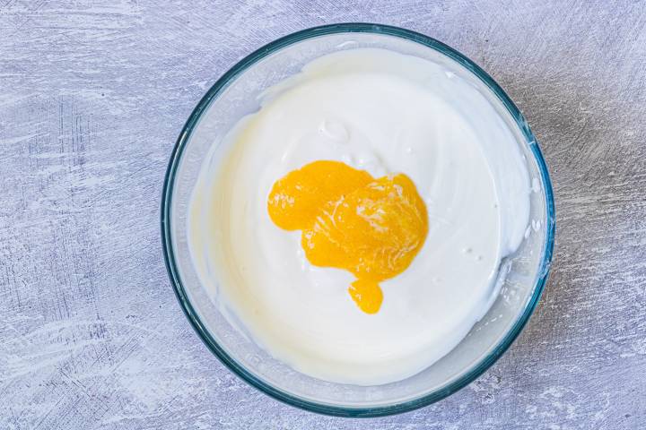 Greek yogurt, honey, and peach puree in a glass bowl.
