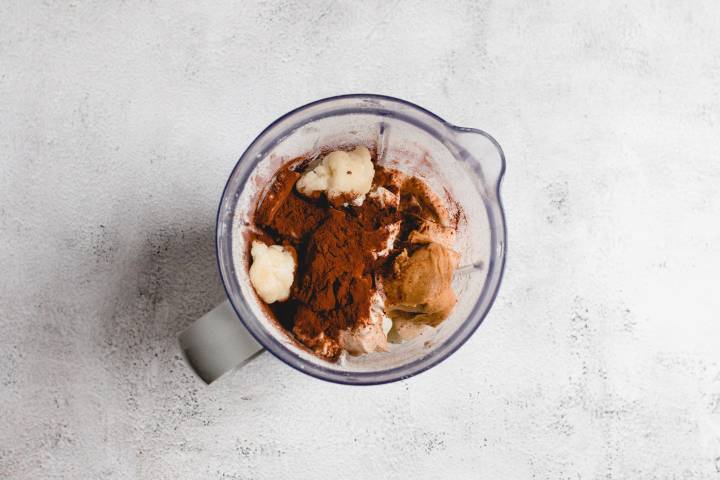 Cauliflower, bananas, oats, cocoa powder, and peanut butter in a blender.