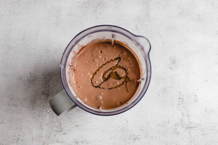 Chocolate, peanut butter, and banana smoothie in a blender with a drizzle of honey. 