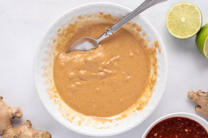 Melted peanut butter in a small white bowl with a spoon.