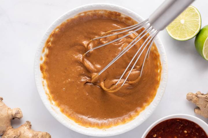 Peanut sauce being stirred by a small whisk.