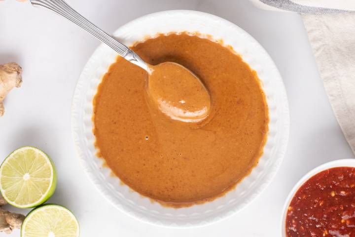 Creamy peanut sauce in a bowl with a spoon.