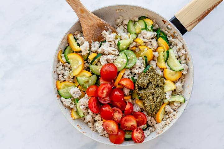 Cherry tomatoes, zucchini, yellow squash, and ground turkey in a skillet with pesto.