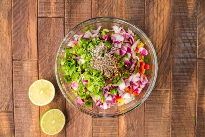 Ingredients for grilled pineapple salsa chopped and added to a glass bowl.