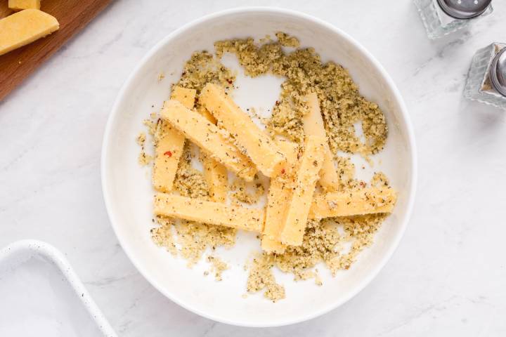 Polenta french fries being tossed with Parmesan cheese and Italian seasoning.