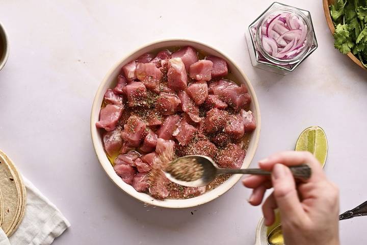 Pork tenderloin pieces marinating with lime juice, orange juice, and spices.