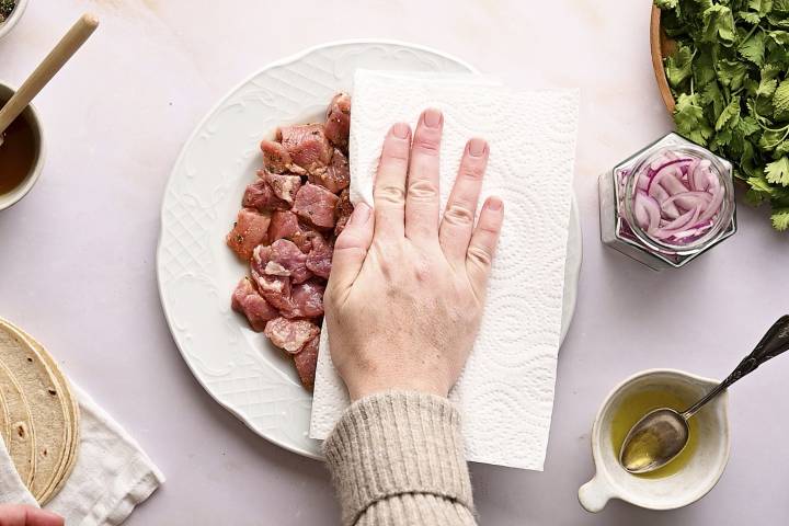 Pork pieces being dried with a paper towel.