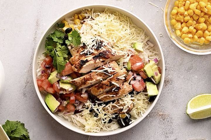 Chicken and rice bowl with steamed rice, chicken, black beans, corn, pico de gallo, avocado, and cilantro.