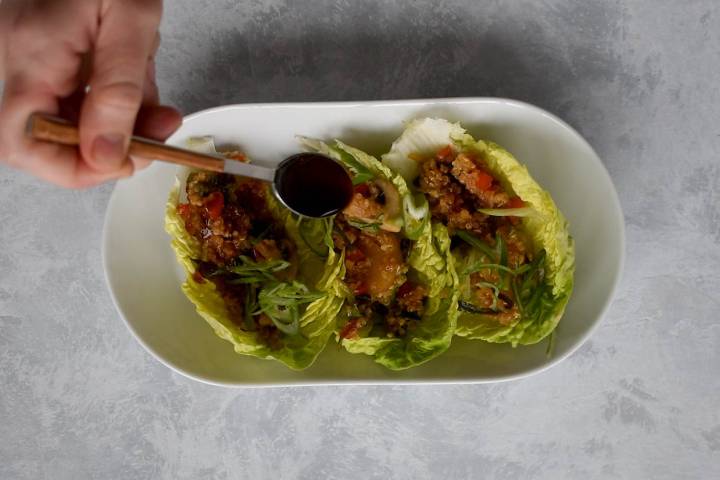 Quinoa lettuce wraps with hoisin sauce being drizzled on top.