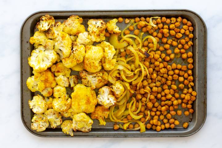 Roasted cauliflower, chickpeas, and onions with curry powder on a baking sheet,
