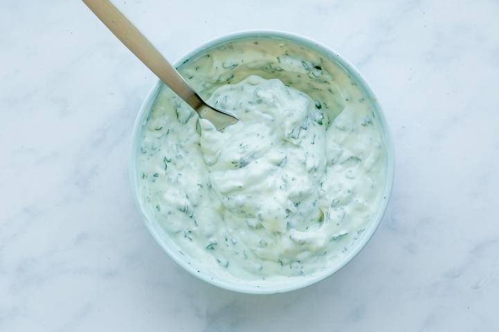 Garlic cilantro yogurt sauce in a small bowl with a spoon.