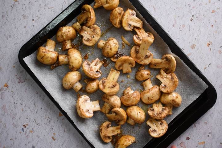 Mushroom halves spread out in a single layer on a baking sheet.