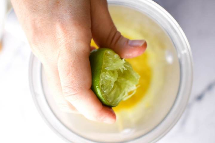 Lime juice being added to homemade green salsa in a blender.