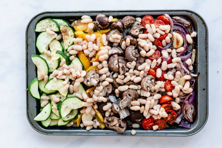 Roasted vegetables on a baking sheet with white beans.