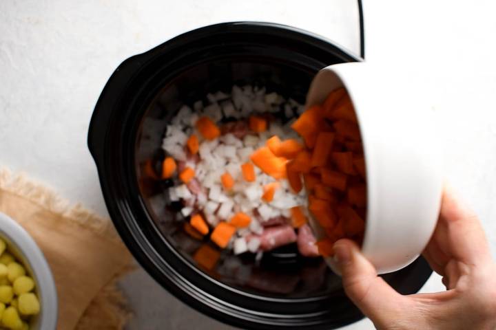 Sausage, onion, carrots, celery, chicken broth, mushrooms, and diced tomatoes in a slow cooker.