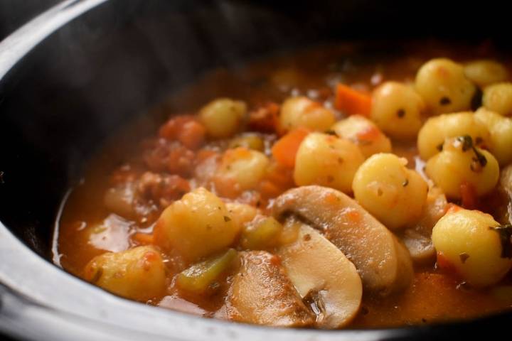 Sausage and potato gnocchi soup in a slow cooker with herbs.