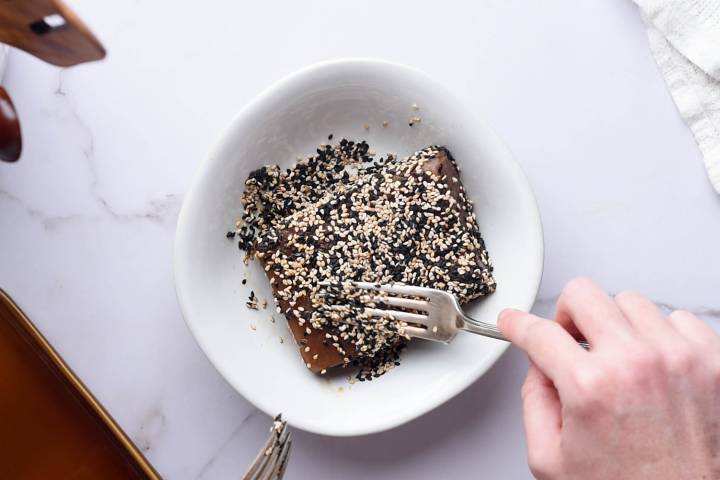Tuna being pressed into black and white sesame seeds.