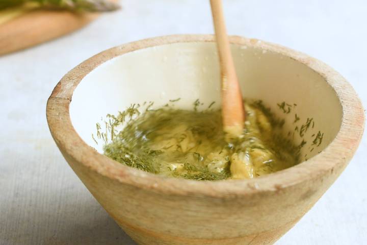 Lemon, Dijon mustard, and dill being mixed in a small bowl.