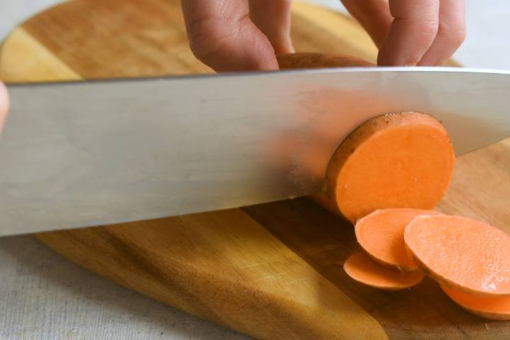 Sweet potatoes being cut into very thin chips.