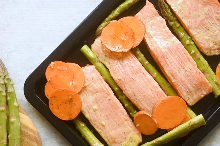 Salmon, asparagus, and sweet potatoes on a baking sheet.
