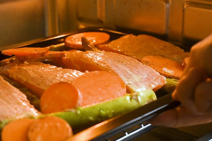 Sheet pan salmon with vegetables baking in the oven.