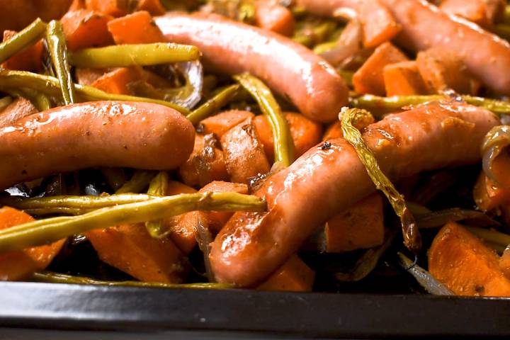 Cooked sheet pan sausages, sweet potatoes, and green beans in the oven.