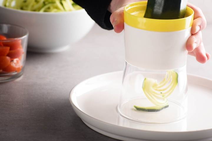 Zucchini noodles being made with a spiralizer.