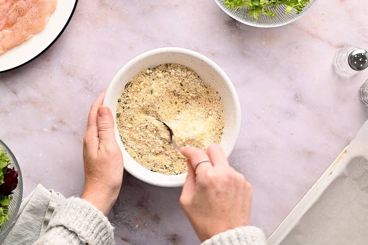 Parmean cheese, breadcrumbs, and garlic powder being mixed together in a bowl.