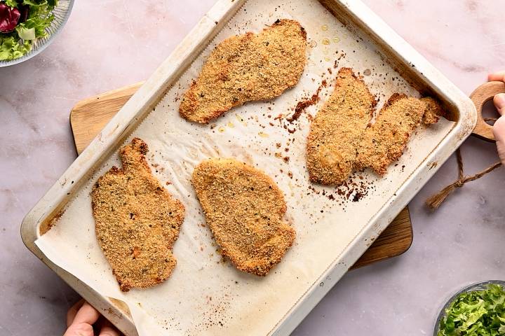 Baked crispy chicken cutlets on a baking sheet.