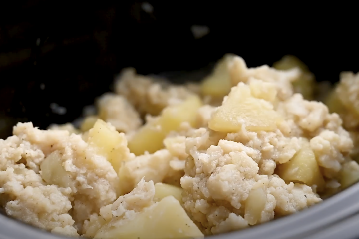 Cooked cauliflower florets and potatoes in a slow cooker.