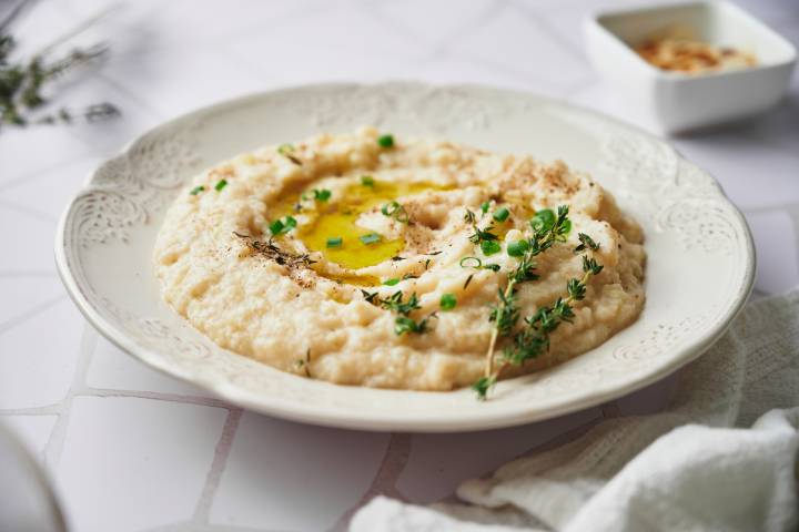 Cauliflower mashed potatoes in a white bowl drizzled with olive oil.